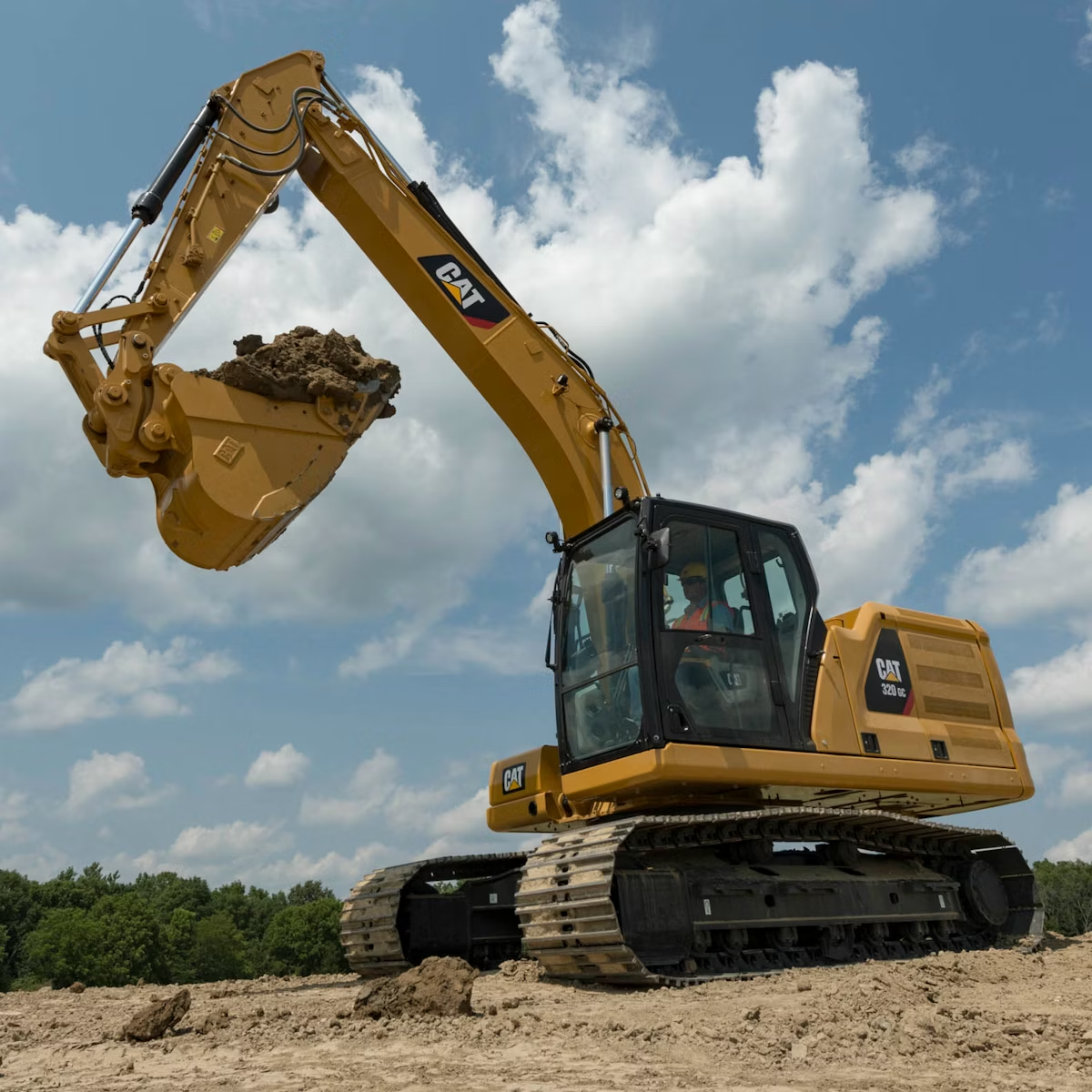 CAT excavator clearing wooded lot at sunset
